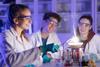 Students in protective lab clothing, working together around beakers and burning magnesium