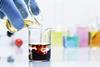 Pouring light yellow iron chloride solution into a beaker of clear potassium thiocyanate solution causing a chemical reaction changing the colour of the liquid to dark red