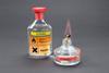 A glass bottle of ethanol labelled highly flammable and harmful with ethanol burning in a spirit burner