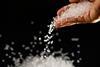 Colourless plastic pellets  fall from a hand against a black background