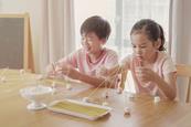 Photo of two children building pyramids out of spaghetti and marshmallows