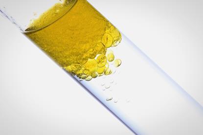 A close-up photograph of a glass test tube containing water and oil