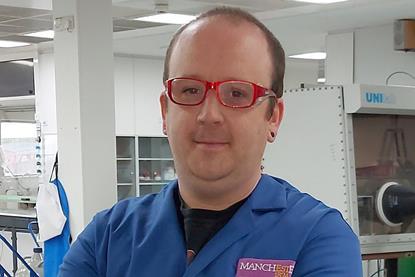A man in a blue lab coat with red glasses in a modern laboratory