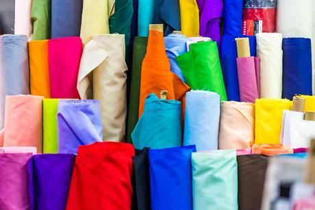 Bolts of colourful cloth on sale at local fabric market store.